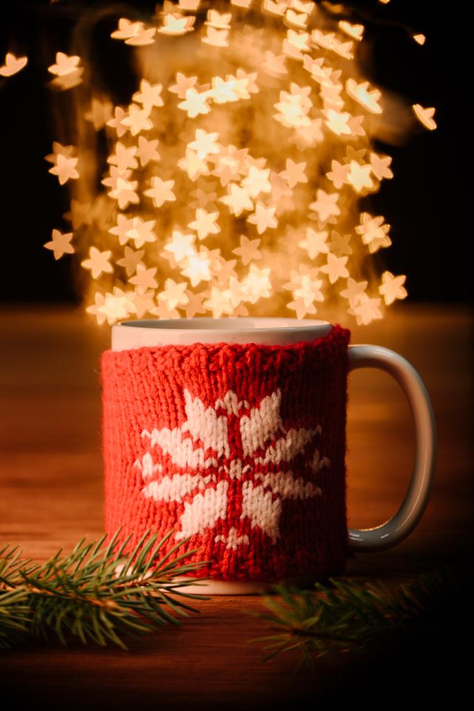 close up view of cup of hot drink and pine tree branches on wooden tabletop with stars bokeh lights background - Photo, Image