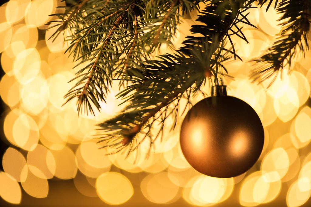 Закрыть вид на золотой рождественский бал висящий на сосне на фоне боке огней
 - Фото, изображение