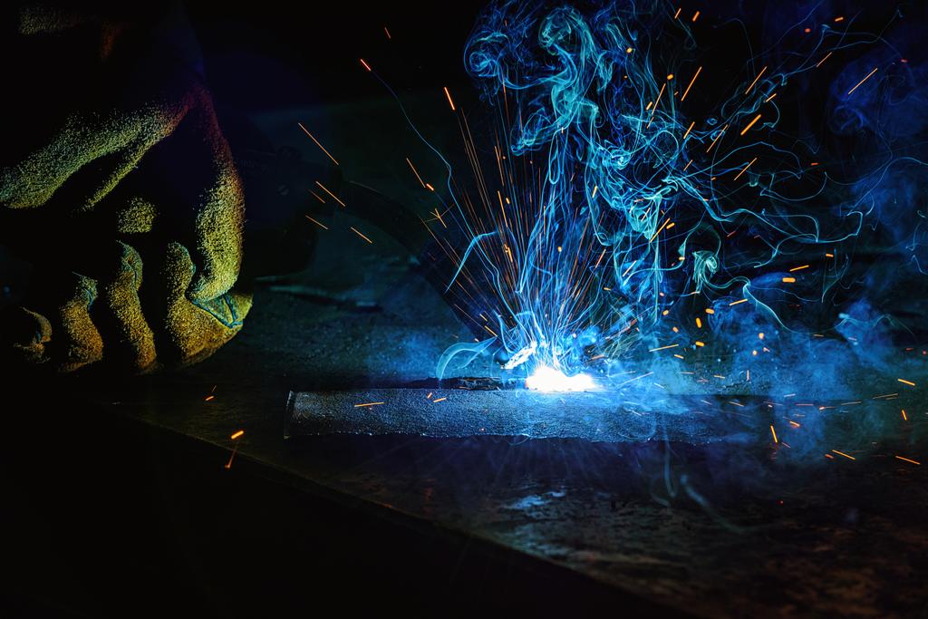 částečný pohled pracovníka svařování kovů s jiskry v továrně  - Fotografie, Obrázek