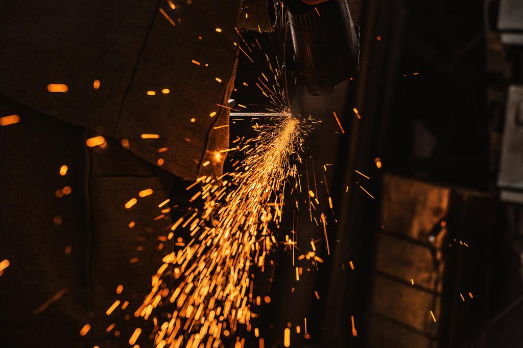 oříznutý obraz dělník výroby pomocí kotoučové pily se leskne v továrně - Fotografie, Obrázek