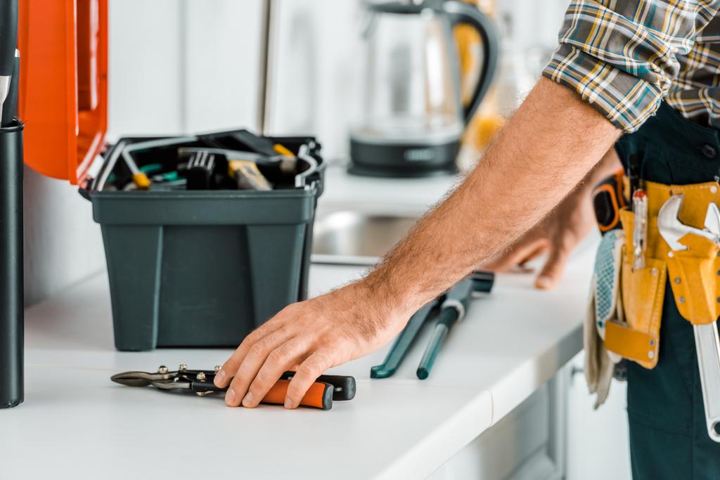 cropped image of plumber putting tools on kitchen counter in kitchen - Photo, Image