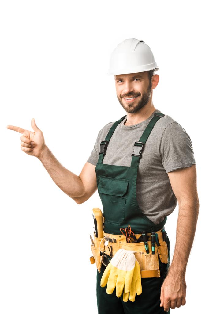 smiling handsome electrician pointing on something isolated on white - Photo, Image