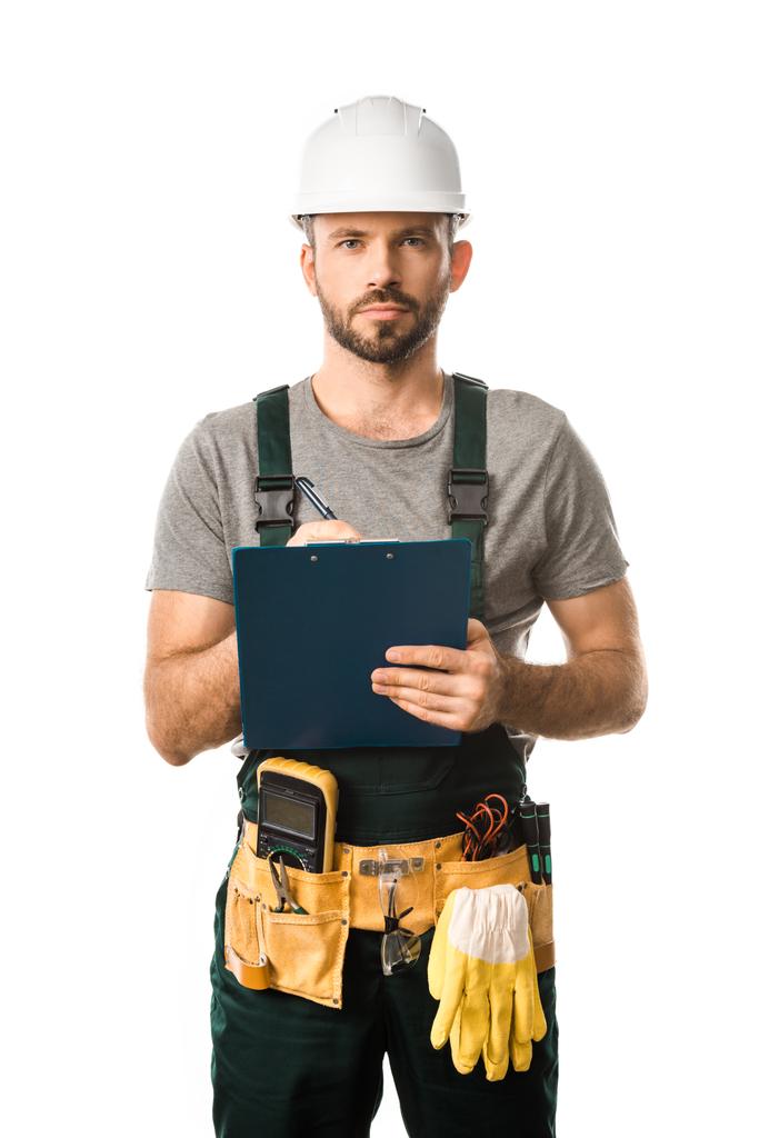 handsome electrician holding clipboard and looking at camera isolated on white - Photo, Image
