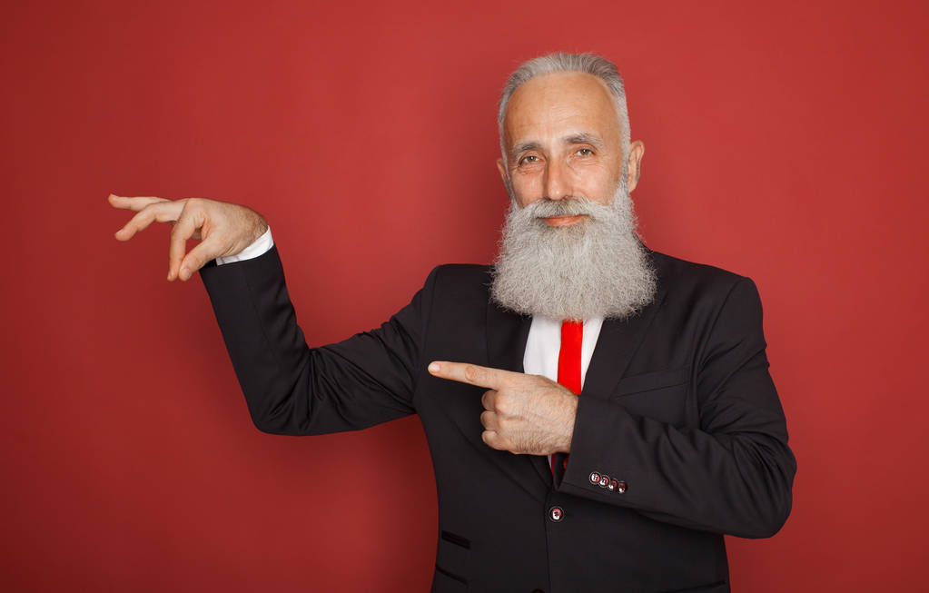 Homme âgé barbu souriant et tenant quelque chose d'imaginaire dans une main sur fond rouge
 - Photo, image
