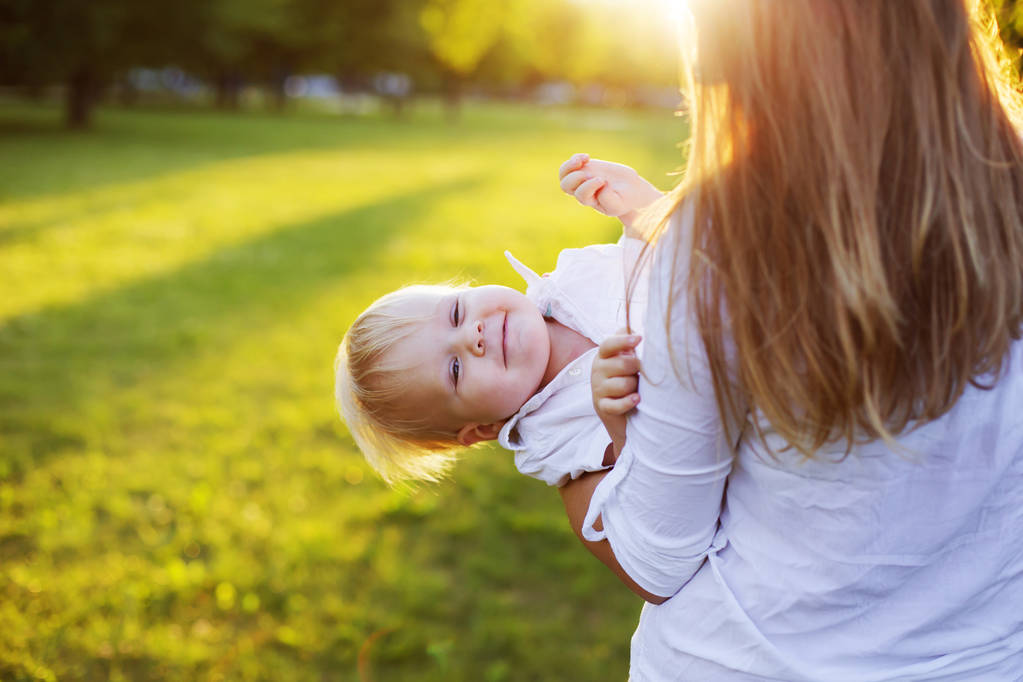 Szczęśliwa kobieta gra na syna malucha w słoneczny park - Zdjęcie, obraz