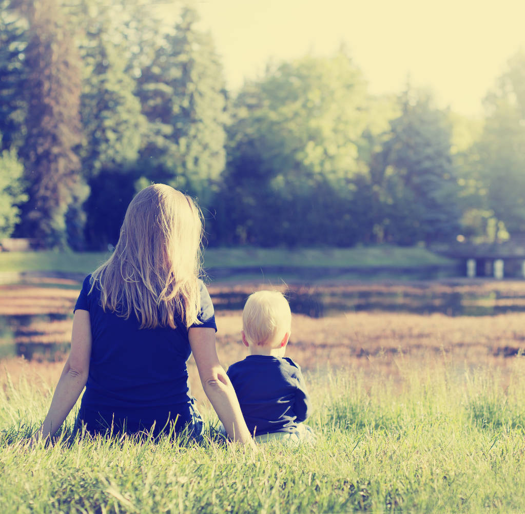 vista trasera de la madre y el hijo sentado y mirando al lago
 - Foto, Imagen