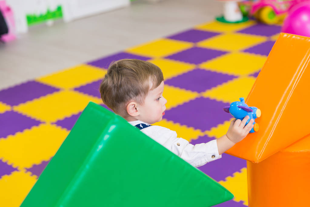 Μερική άποψη του χαριτωμένο μικρό αγόρι που παίζει με το παιχνίδι στην αίθουσα παιχνιδιών - Φωτογραφία, εικόνα