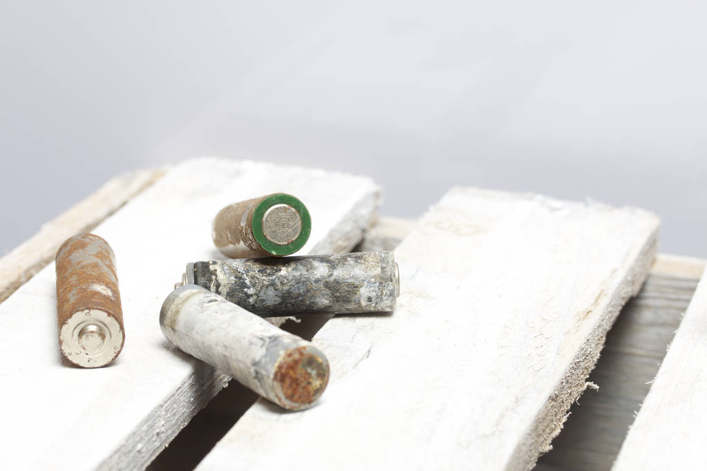 Baterías usadas con heridas en los dedos cubiertas de corrosión. Se acuestan en una caja de madera. Reciclaje
. - Foto, imagen
