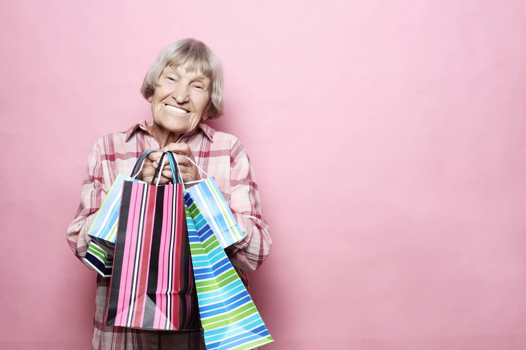 Bonne grand-mère avec des sacs à provisions sur fond rose. Style de vie et concept de personnes
. - Photo, image