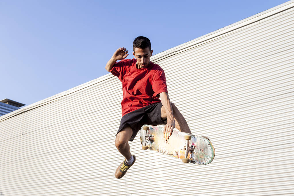 młody Skater podskakuje z jego pokładzie przed metalowe podłoże na dachach opuszczony budynek - Zdjęcie, obraz