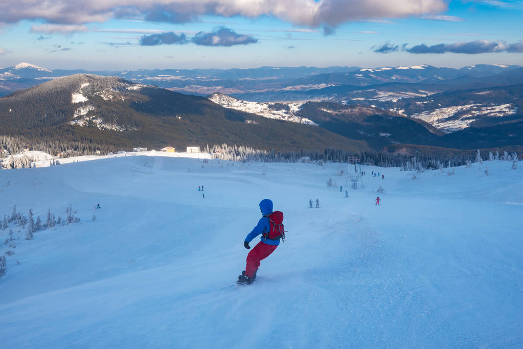 Sırt çantası ile snowboard ile ufka uzanan arka plan sıradağları üzerinde bir kar fırtınası sırasında dağ yokuş aşağı gidiyor. Geniş açı, arkadan görünüm. - Fotoğraf, Görsel
