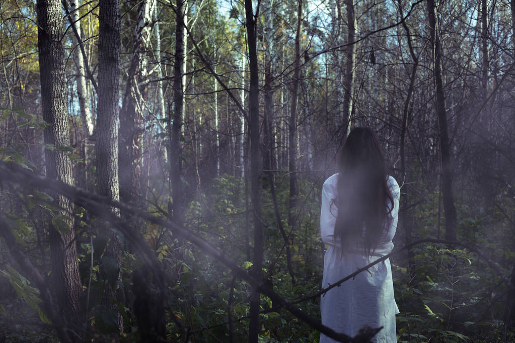 暗い森でハロウィーンに死んだ女の子の肖像画。ハロウィーンの夜に暗い暗い森の幽霊少女 - 写真・画像