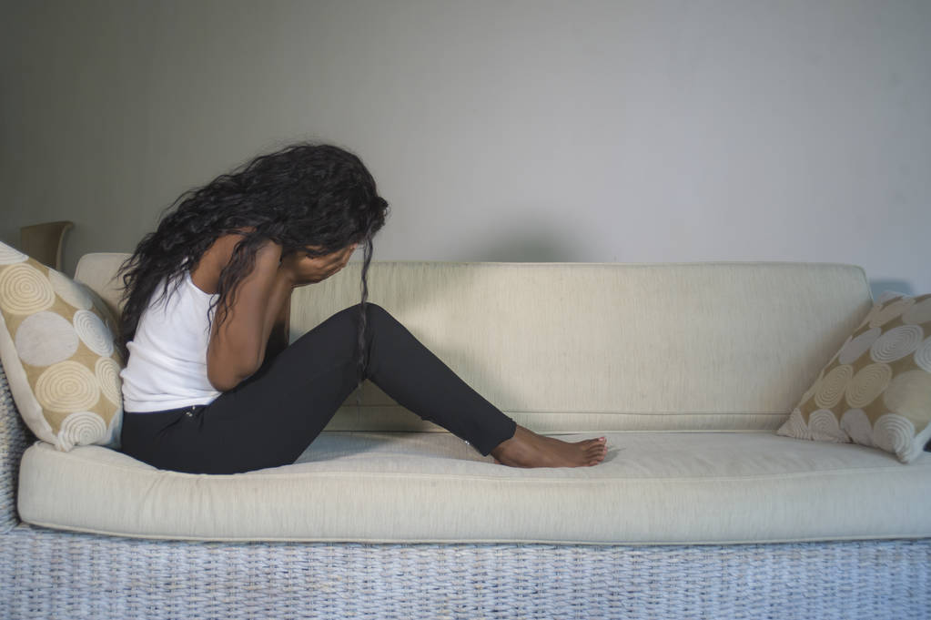 fiatal, vonzó és szomorú, fekete-afrikai-amerikai nő ül otthon depressziós kanapé kanapé érzés ideges és csalódott, szenvedés probléma depresszió és szorongás válság sírás kétségbeesett - Fotó, kép