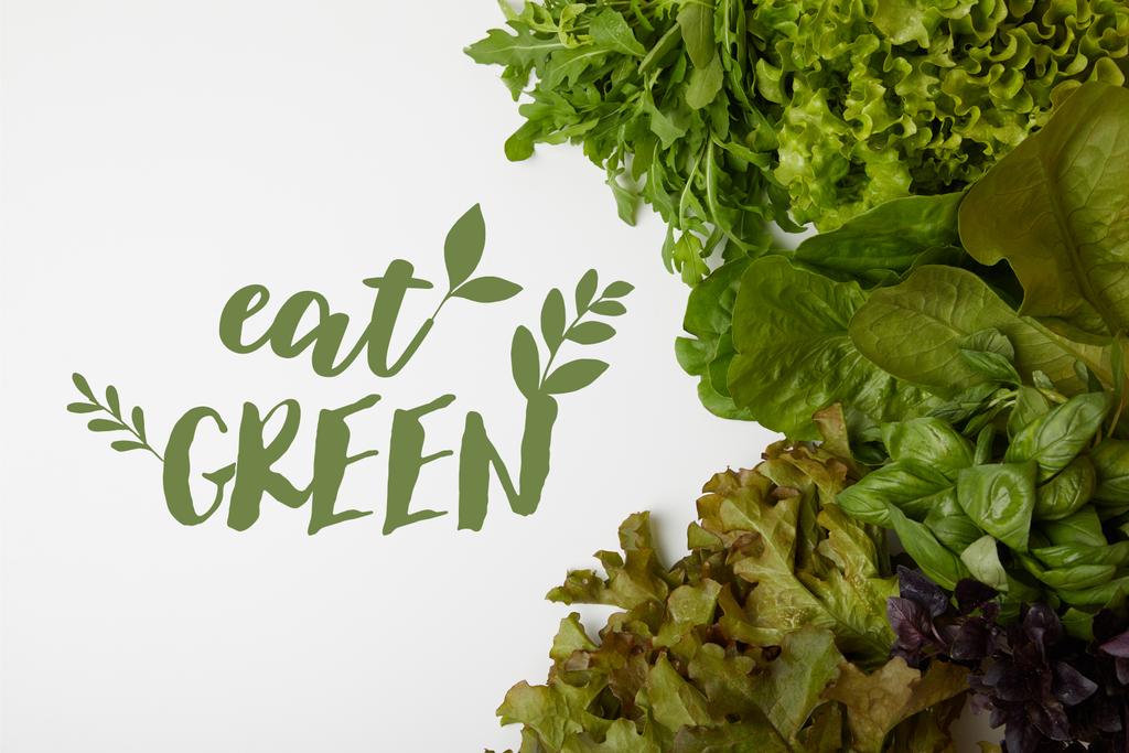 vista superior de las verduras frescas de varias hojas en la superficie blanca con letras "comer verde"
 - Foto, Imagen