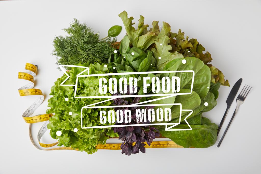 vista superior de varias verduras maduras en caja con cubiertos y cinta métrica en la superficie blanca con inspiración de "buena comida - buen humor"
 - Foto, Imagen