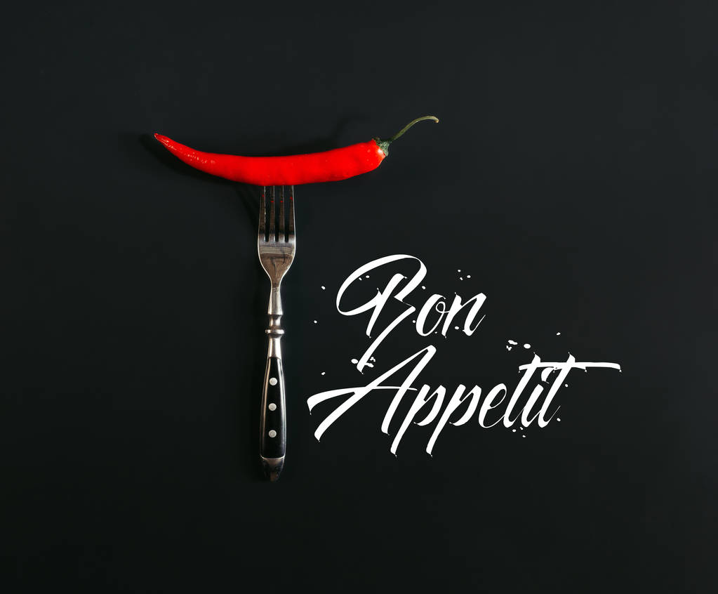 czerwona papryczka chili na widelec na czarno z napisem "bon appetit" - Zdjęcie, obraz