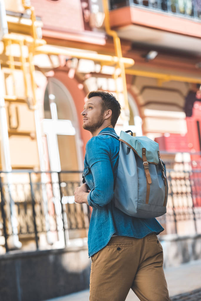 attrayant jeune touriste avec sac à dos marchant par la rue et levant les yeux
 - Photo, image
