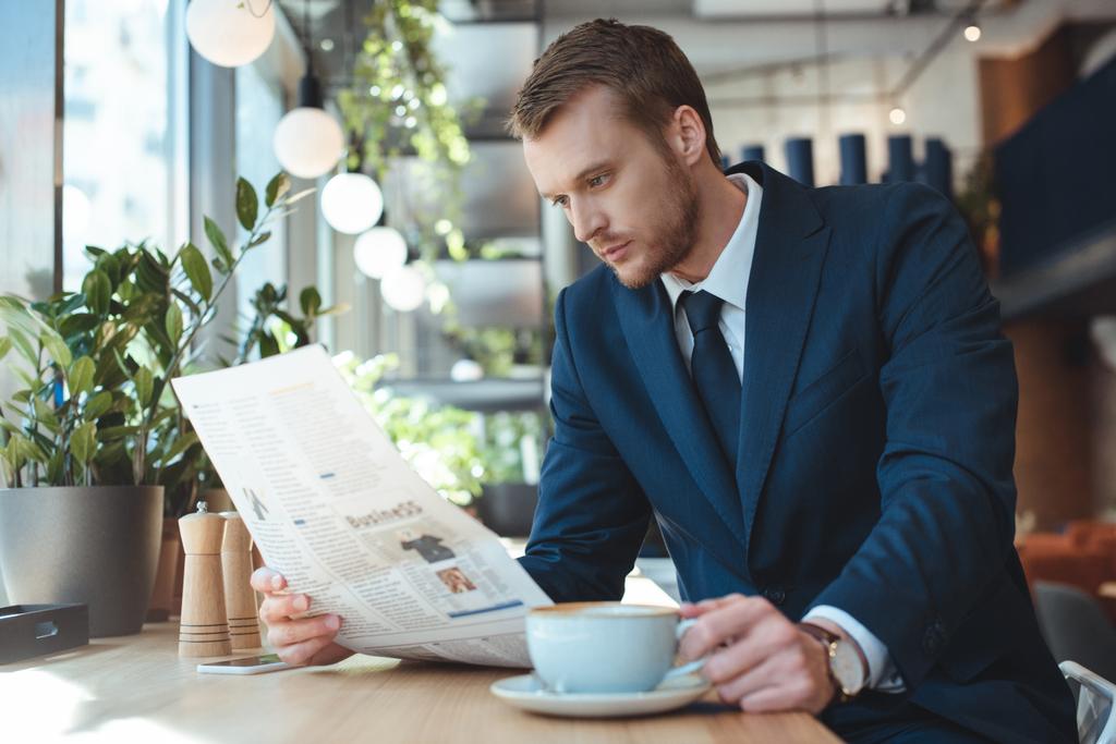 businessman with cup of coffee reading newspaper during coffee break in cafe - Photo, Image