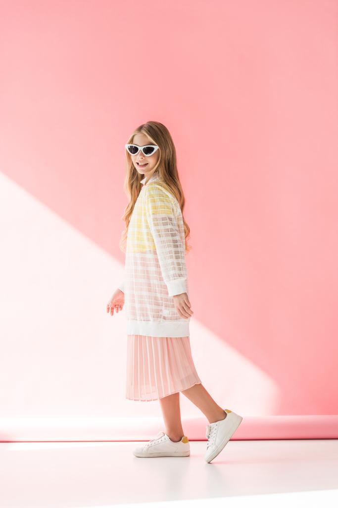 adorável elegante jovem posando em roupas elegantes e óculos de sol em rosa
  - Foto, Imagem