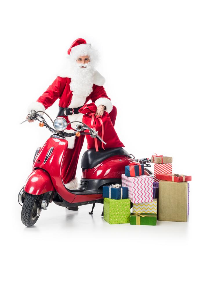 Санта-Клаус в костюме стоял с мешком на Рождество возле скутера и кучей подарочных коробок, изолированных на белом фоне
  - Фото, изображение