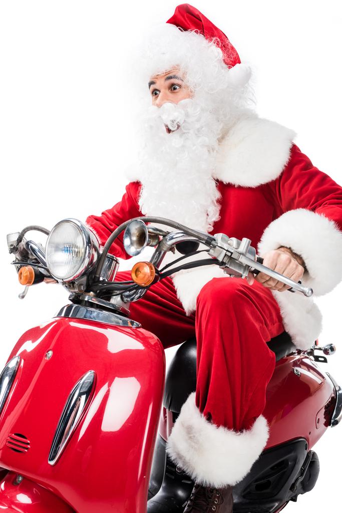 überrascht Weihnachtsmann in Kostüm Reiten auf Roller isoliert auf weißem Hintergrund  - Foto, Bild