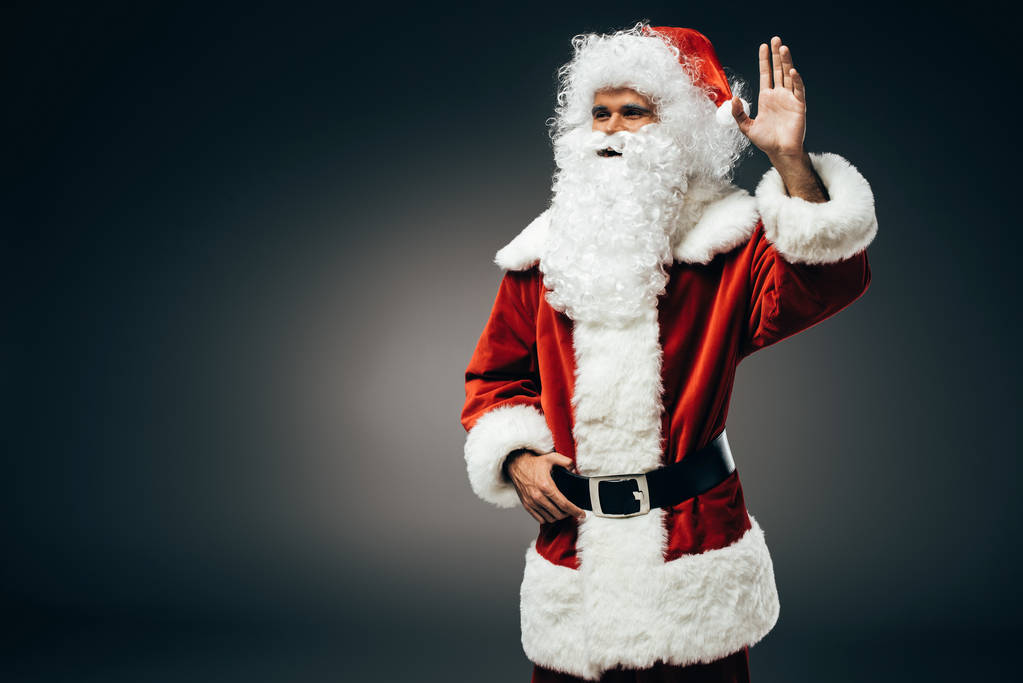 onnellinen joulupukki puku heiluttaa käsin eristetty harmaalla pohjalla
  - Valokuva, kuva