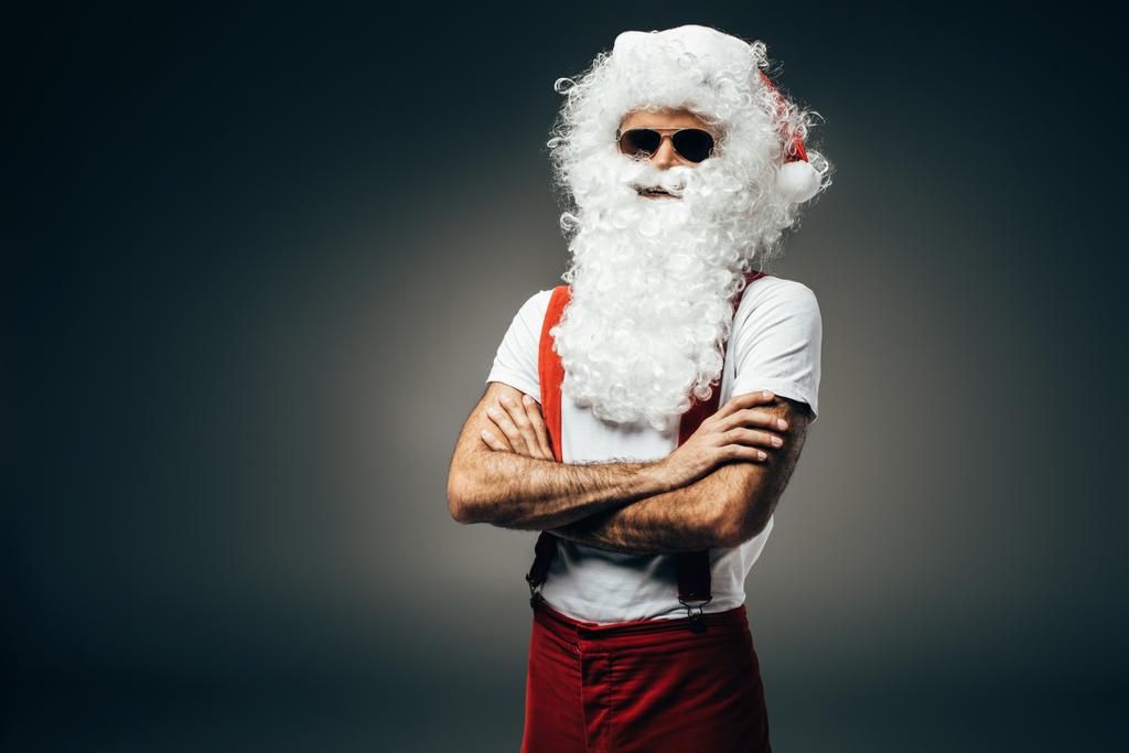 serious santa claus in sunglasses standing with crossed arms isolated on grey background  - Photo, Image