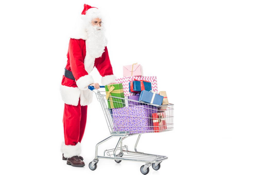 side view of santa claus carrying trolley with pile of gift boxes isolated on white background - Photo, Image
