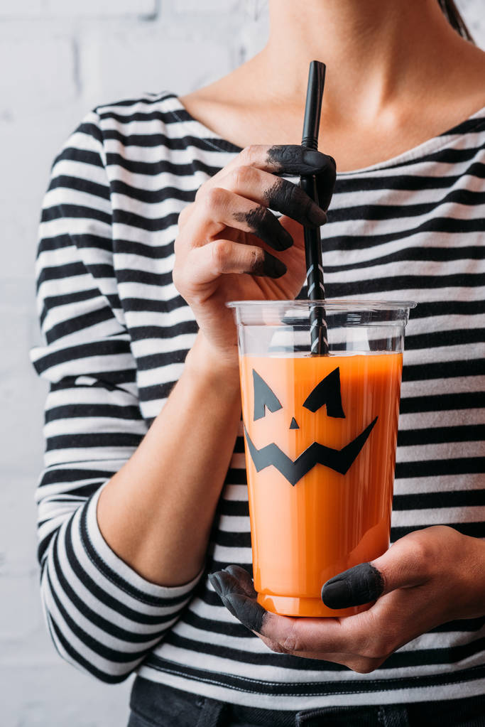 Schnappschuss einer Frau mit einem Glas Kürbissaft im Gesicht, Halloween-Konzept - Foto, Bild