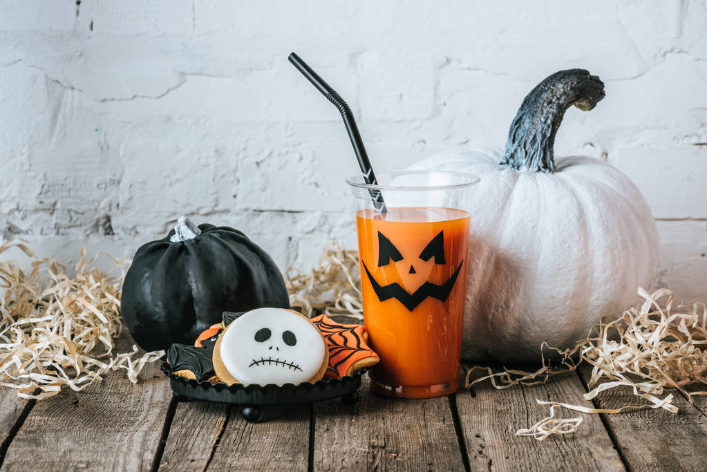 Nahaufnahme von Halloween-Komposition mit Kürbissen, Keksen und einem Glas Kürbissaft - Foto, Bild