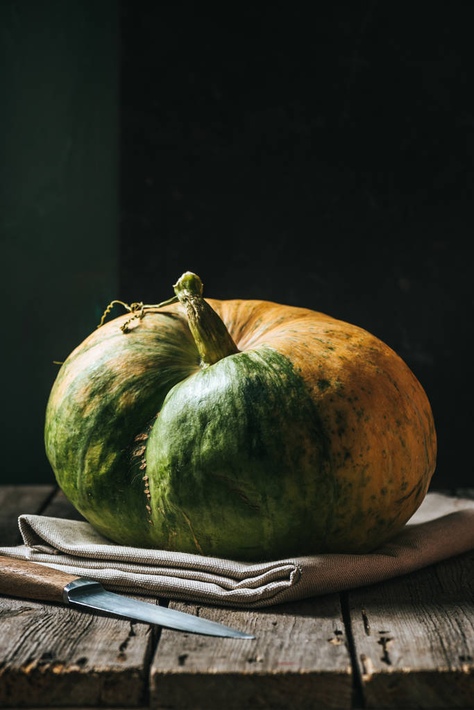 close up view of raw pumpkin on linen and knife on black background - Photo, Image