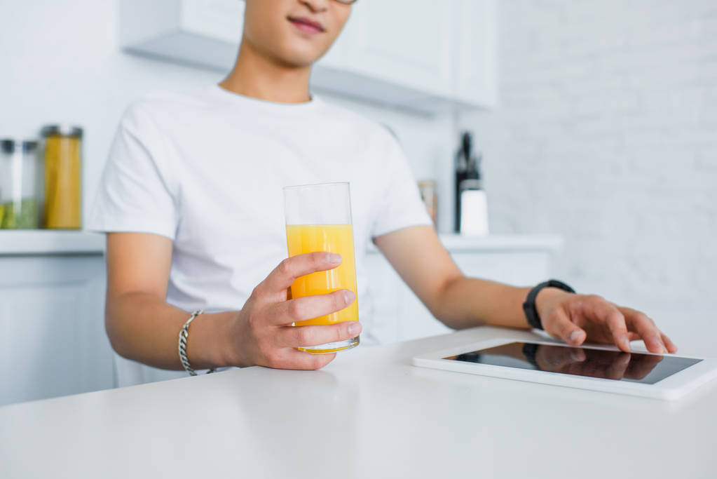 cropped shot of young man holding glass of juice and using digital tablet - Photo, Image