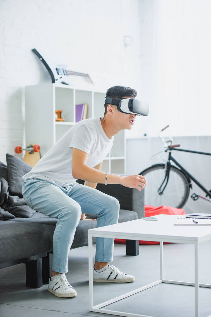 emotional young asian man using virtual reality headset at home  - Photo, Image