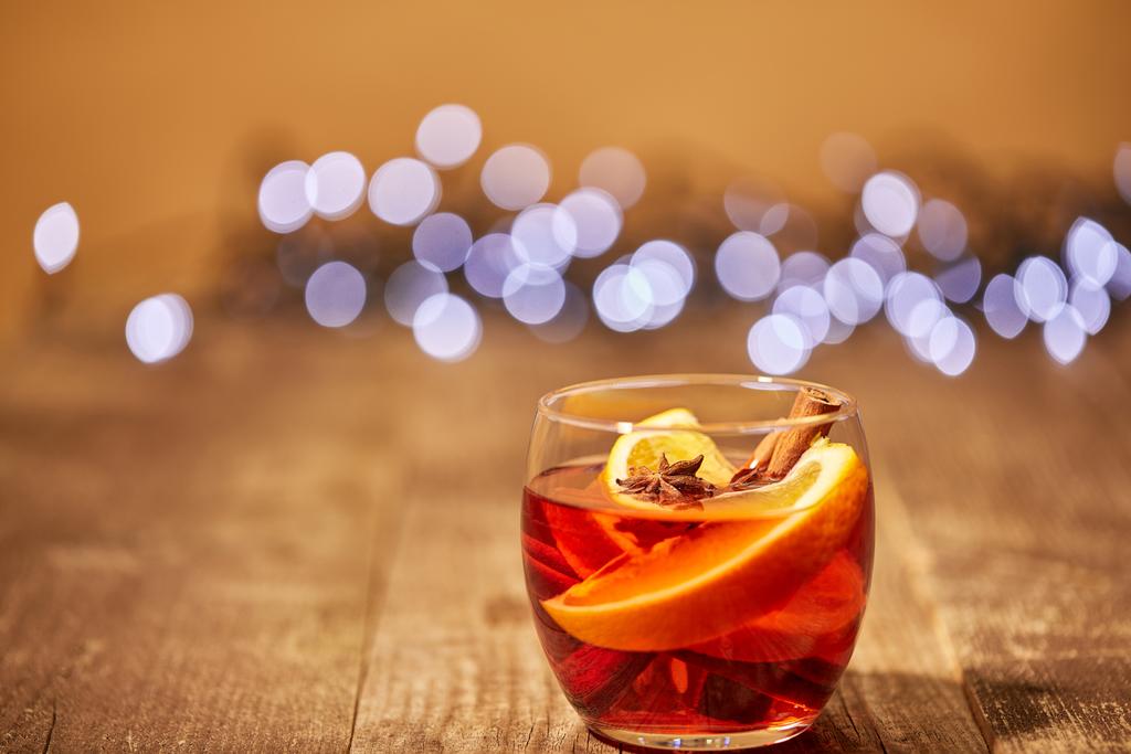 vue rapprochée de la boisson au vin chaud avec des morceaux d'orange et des étoiles d'anis sur la surface en bois avec des lumières bokeh sur le fond
 - Photo, image