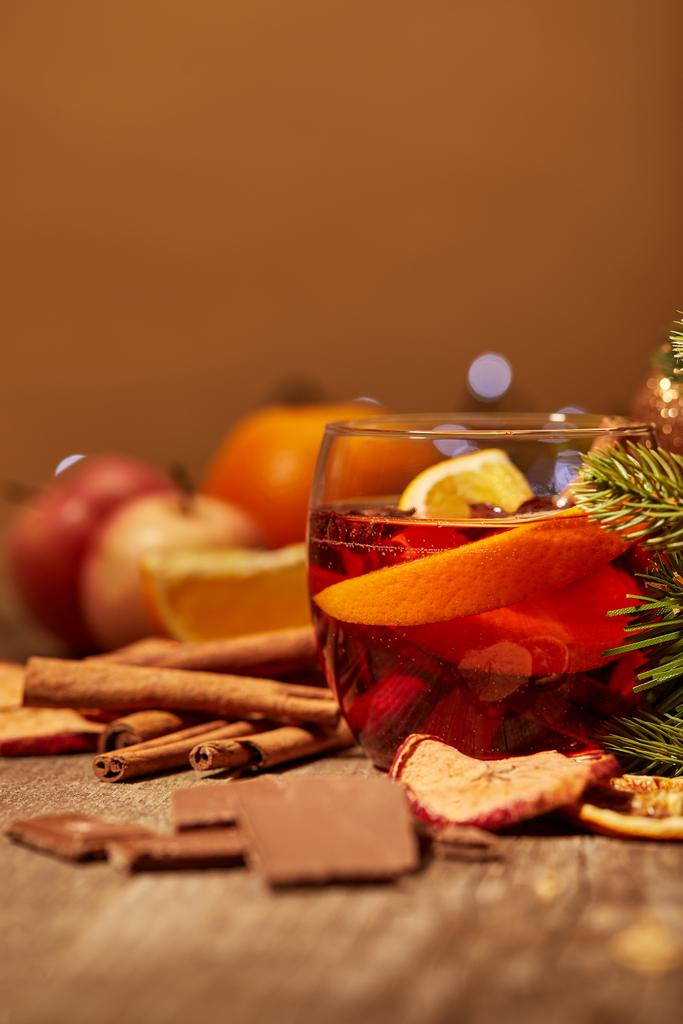 close up view of tasty mulled wine drink, chocolate and pine tree branch on wooden surface - Photo, Image