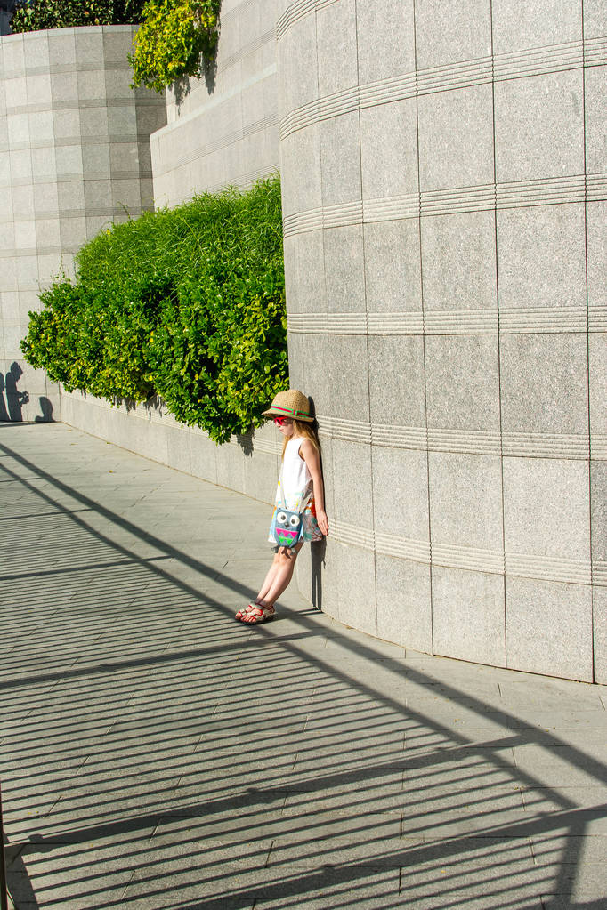 Dívka se postaví ke zdi a podívá se do stínu - Fotografie, Obrázek