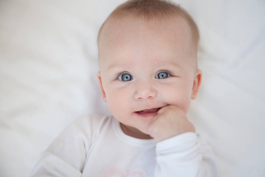 heureux enfant souriant repose sur son dos sur un drap blanc
 - Photo, image