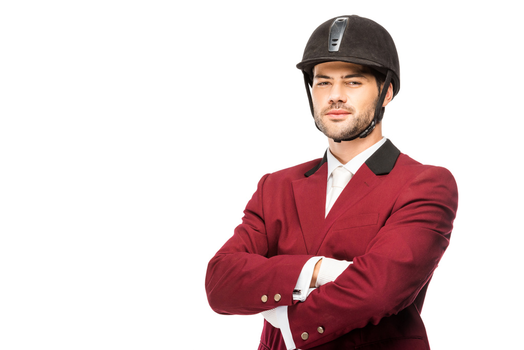 handsome young horseman in uniform and helmet looking at camera with crossed arms isolated on white - Photo, Image