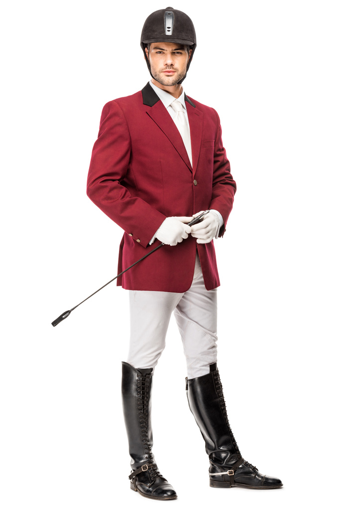 handsome young horseman in uniform holding horseman stick and looking at camera isolated on white - Photo, Image