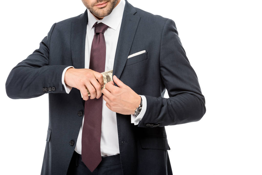 частичный взгляд бизнесмена, помещающего долларовые купюры в карман пиджака изолированного на белом
  - Фото, изображение