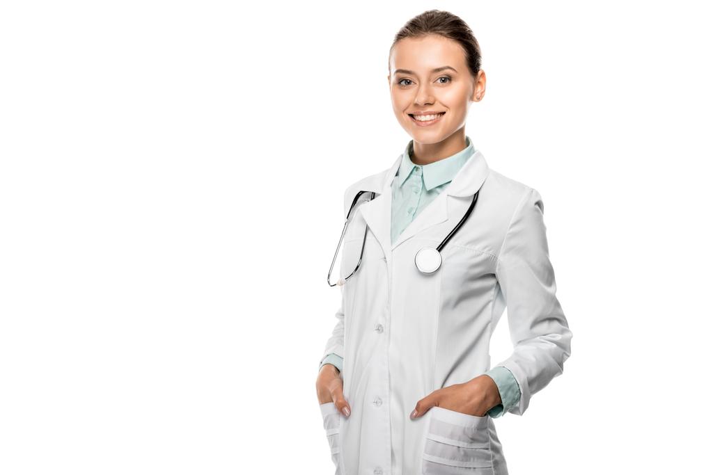 Veselá mladá lékařka s stetoskop přes krk při pohledu na fotoaparát izolované na bílém - Fotografie, Obrázek