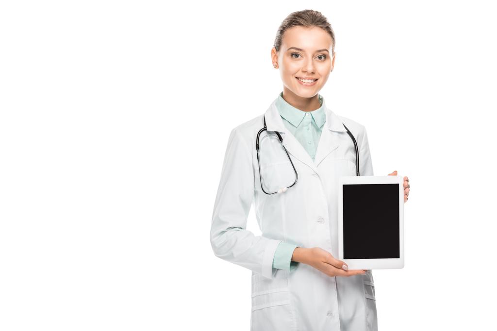 Lächelnde Ärztin im Arztkittel zeigt digitales Tablet mit leerem Bildschirm isoliert auf weißem Hintergrund - Foto, Bild