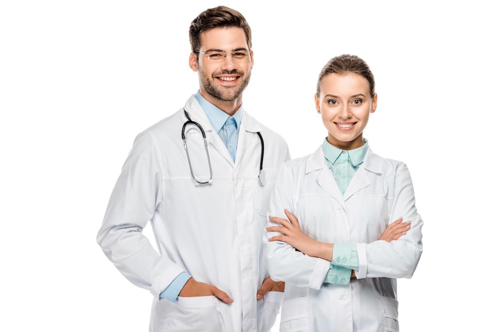 handsome happy male doctor standing near female colleague with crossed arms isolated on white  - Photo, Image