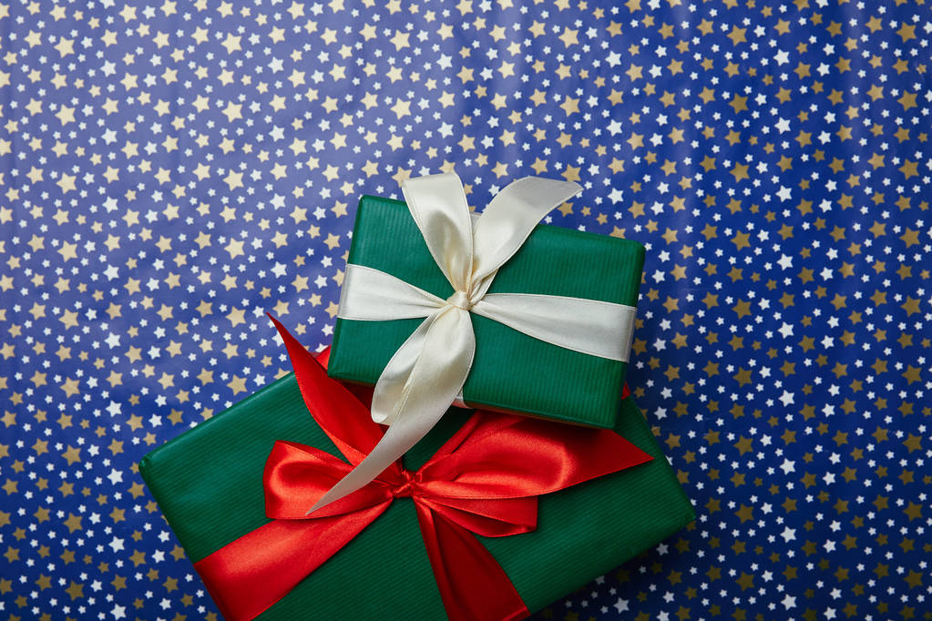 vue du dessus des cadeaux de nouvel an emballés avec des rubans sur papier d'emballage avec motif étoiles
 - Photo, image