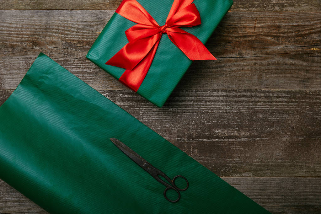 vista dall'alto di carta da regalo verde, forbici e presente con nastro rosso su fondo di legno
 - Foto, immagini