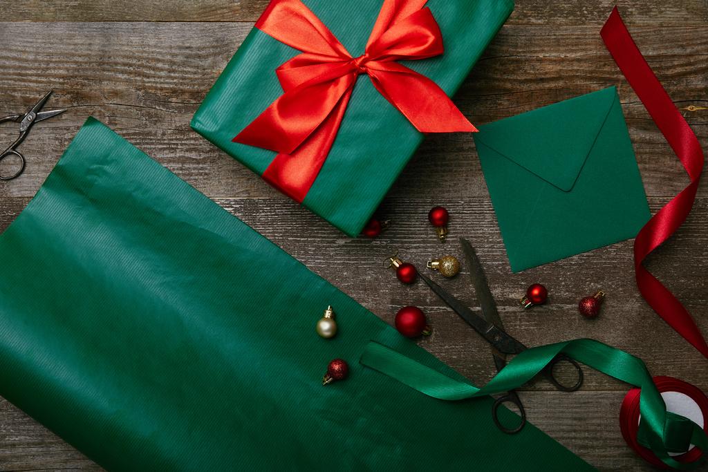 Top van weergave van Kerstmis speelgoed, verpakt met lint en lege enveloppe wenskaart op houten achtergrond presenteren - Foto, afbeelding