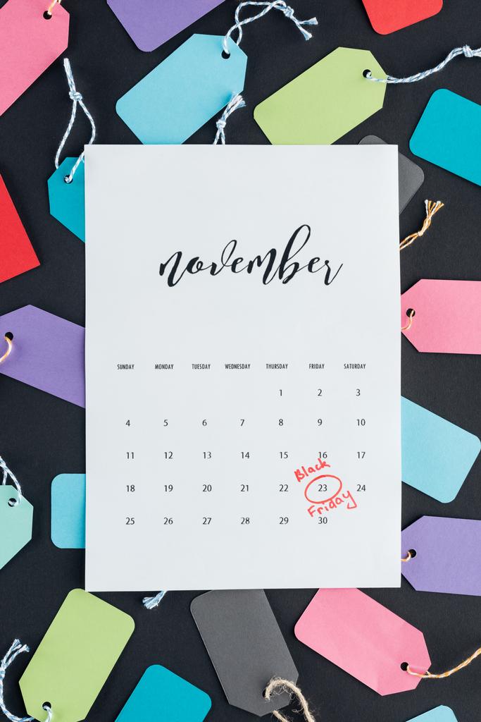 bovenaanzicht van november kalender met zwarte vrijdag ondertekenen op kleurrijke verkoop tags   - Foto, afbeelding