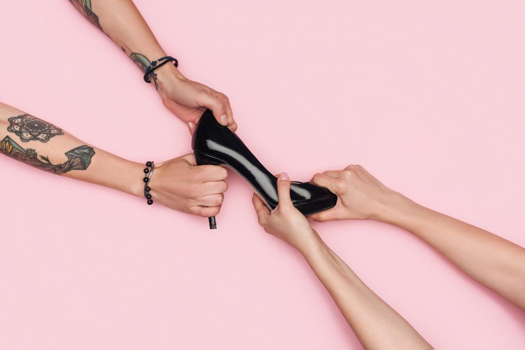 περικοπεί προβολή των γυναικών τράβηγμα ψηλές μαύρες παπούτσι κατά την πώληση που απομονώνονται σε ροζ - Φωτογραφία, εικόνα