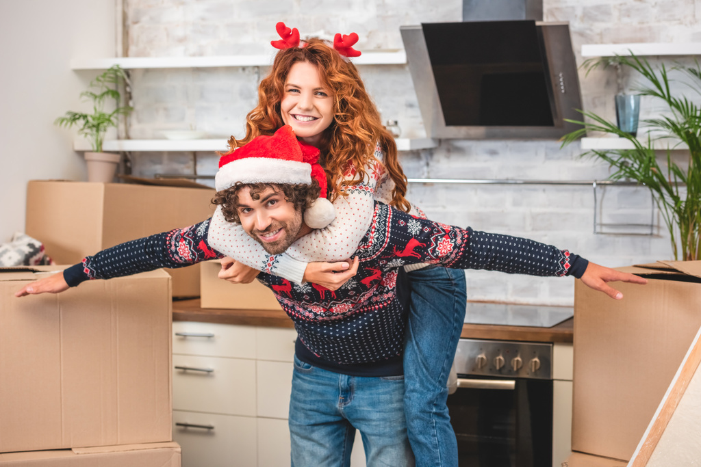 щаслива молода пара розважається і посміхається на камеру під час переїзду в різдвяний час
   - Фото, зображення