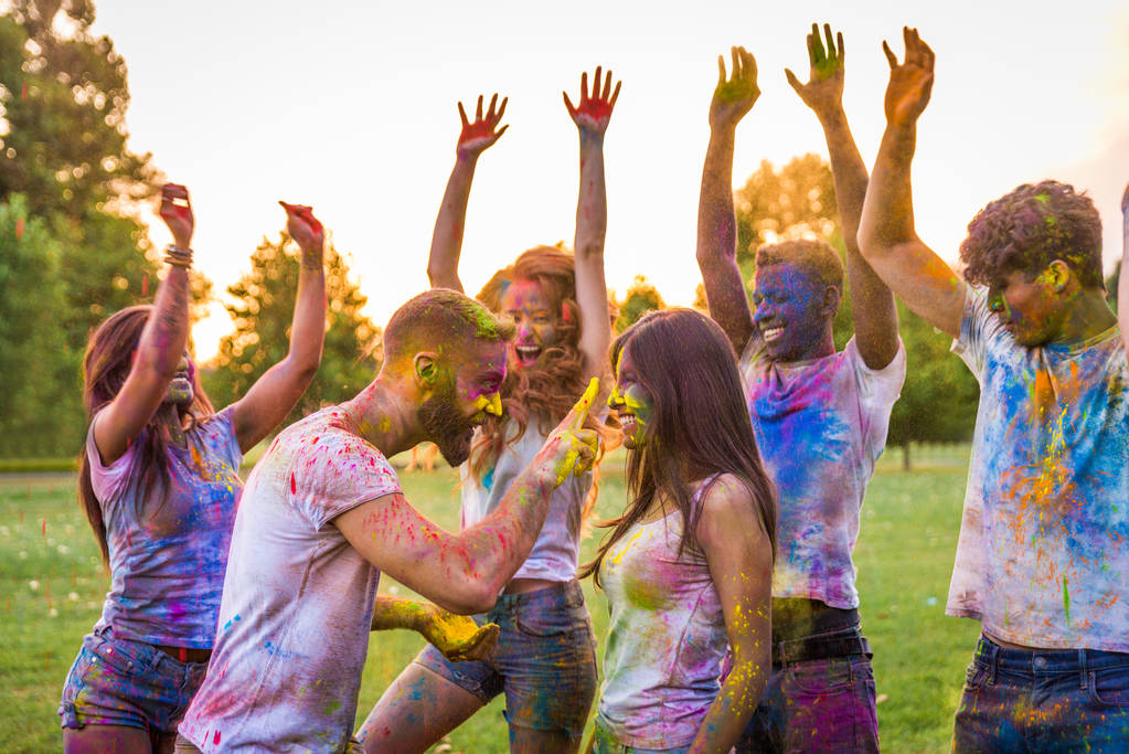 Gruppe glücklicher Freunde, die mit Holi-Farben im Park spielen - junge Erwachsene, die Spaß beim Holi-Festival haben, Konzepte über Spaß, Spaß und junge Generation - Foto, Bild